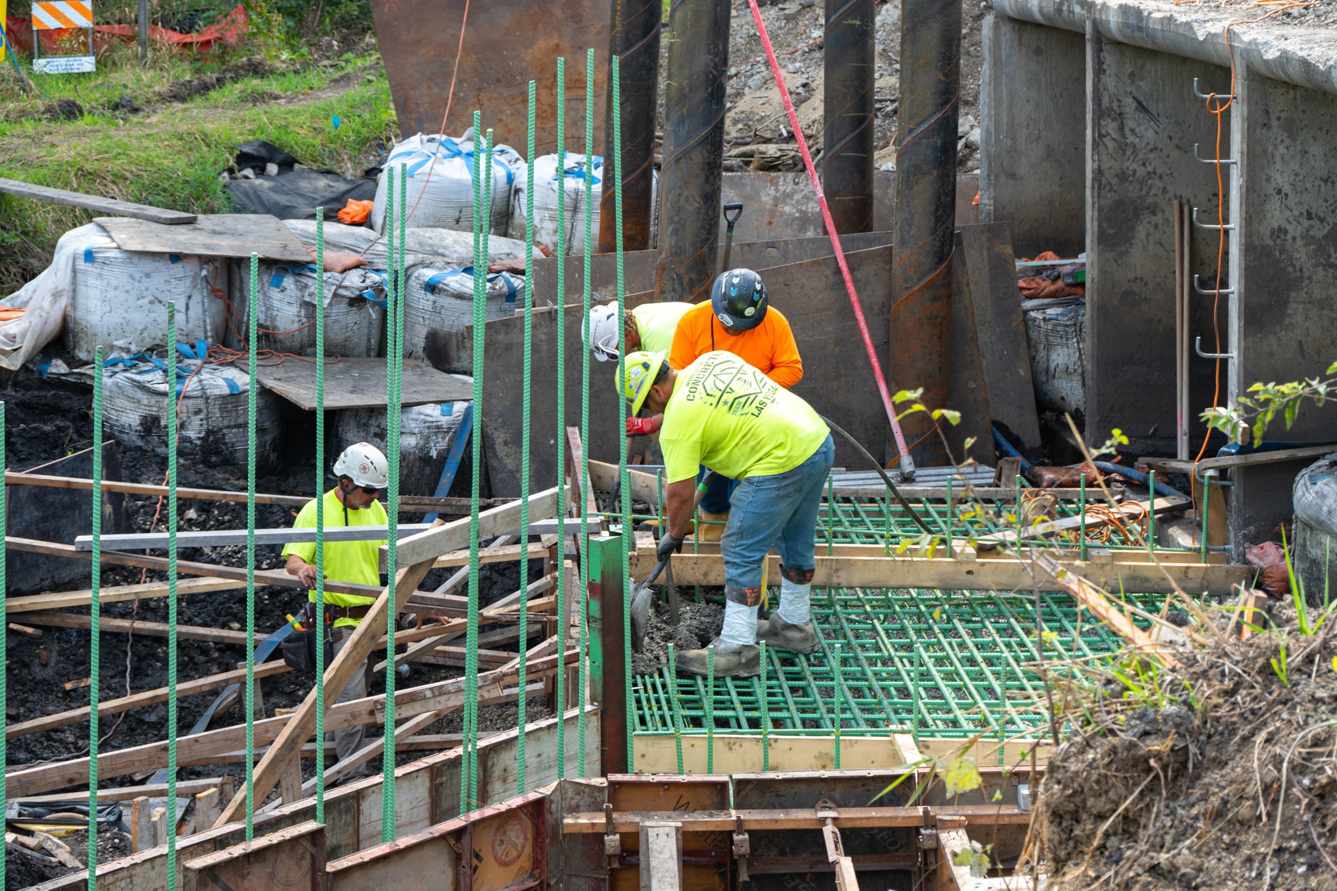 Crews pouring concrete around steel supports